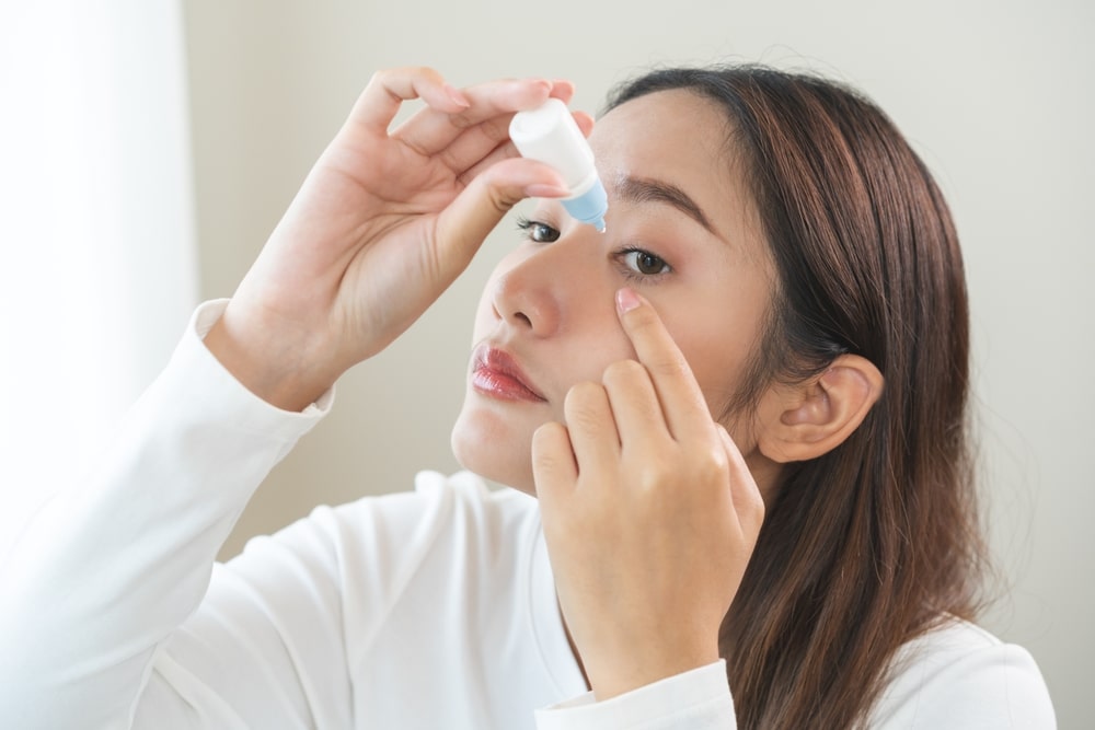 Asian young woman applying medical eye drops